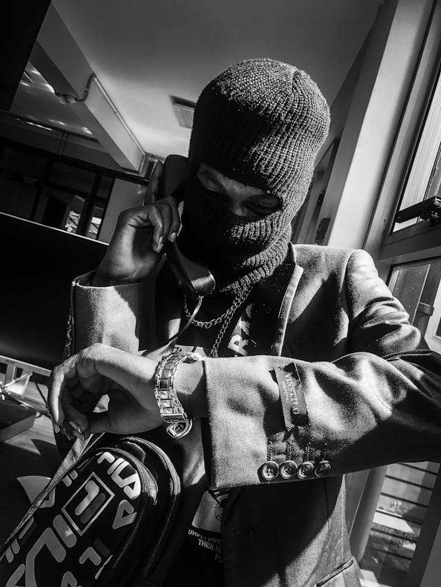 Criminal robber wearing a mask on the phone while looking at his watch